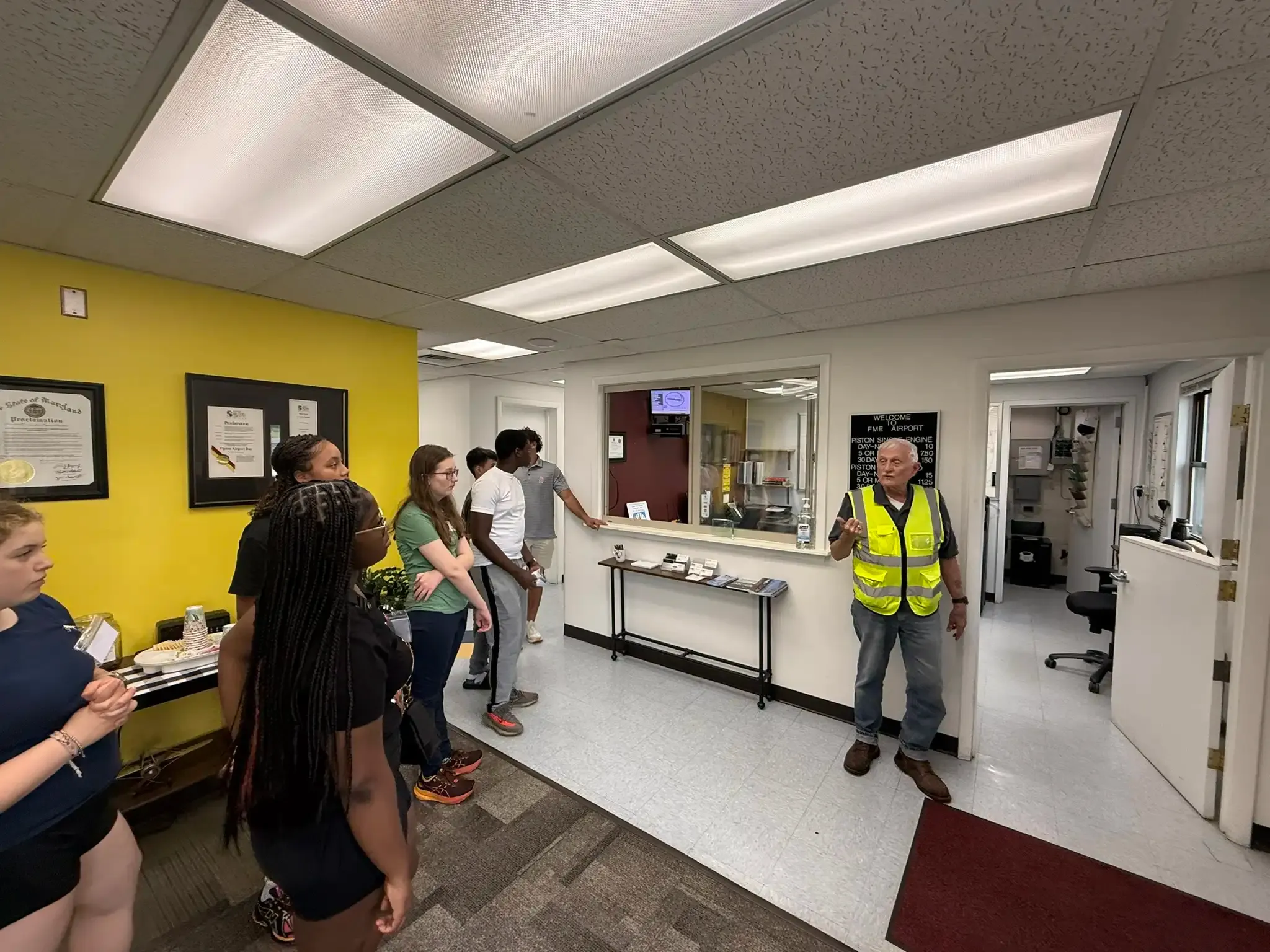Campers touring the Tipton Airport operations office with a member of the airport staff