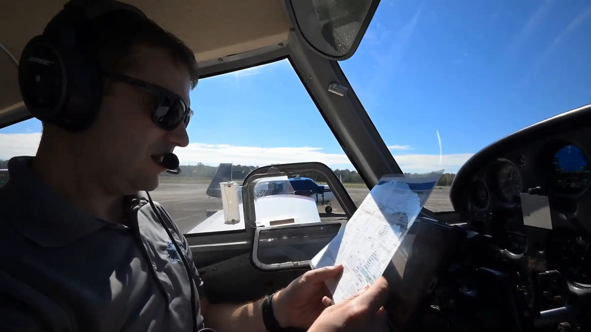Pilot with a headset working through a checklist in the cockpit