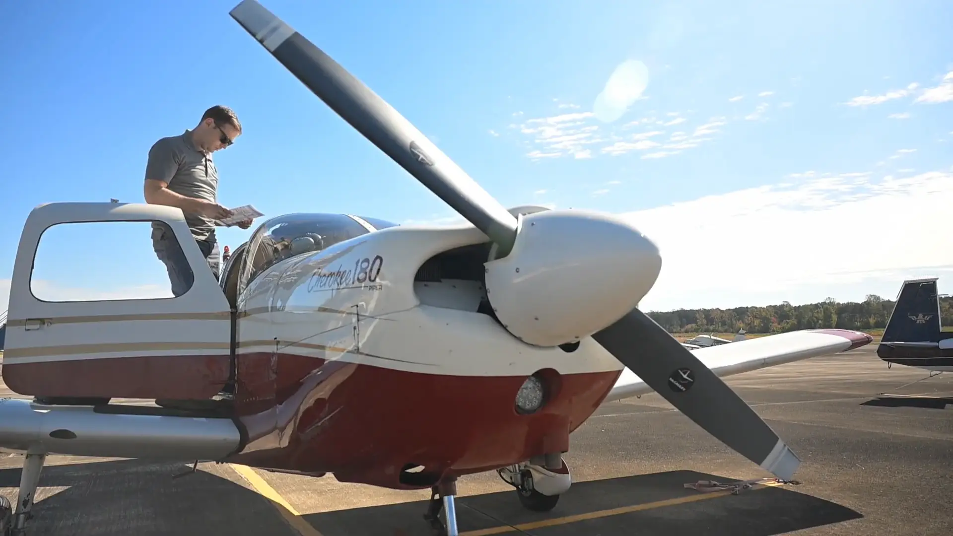 Pilot reviewing a chart on the wing of the training aircraft before a flight