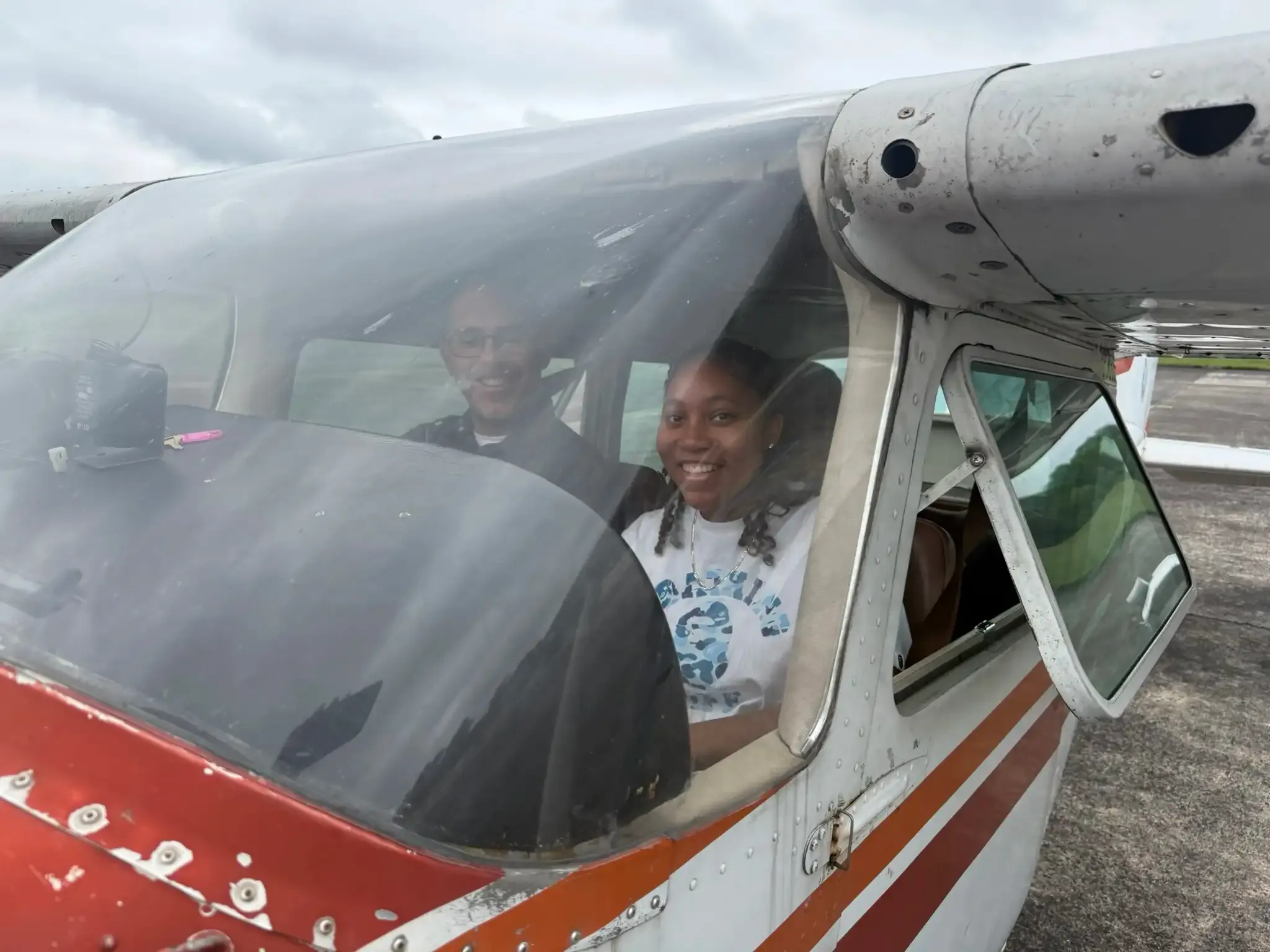 A camper smiling from the cockpit of a Cessna with her flight instructor at Tipton Airport