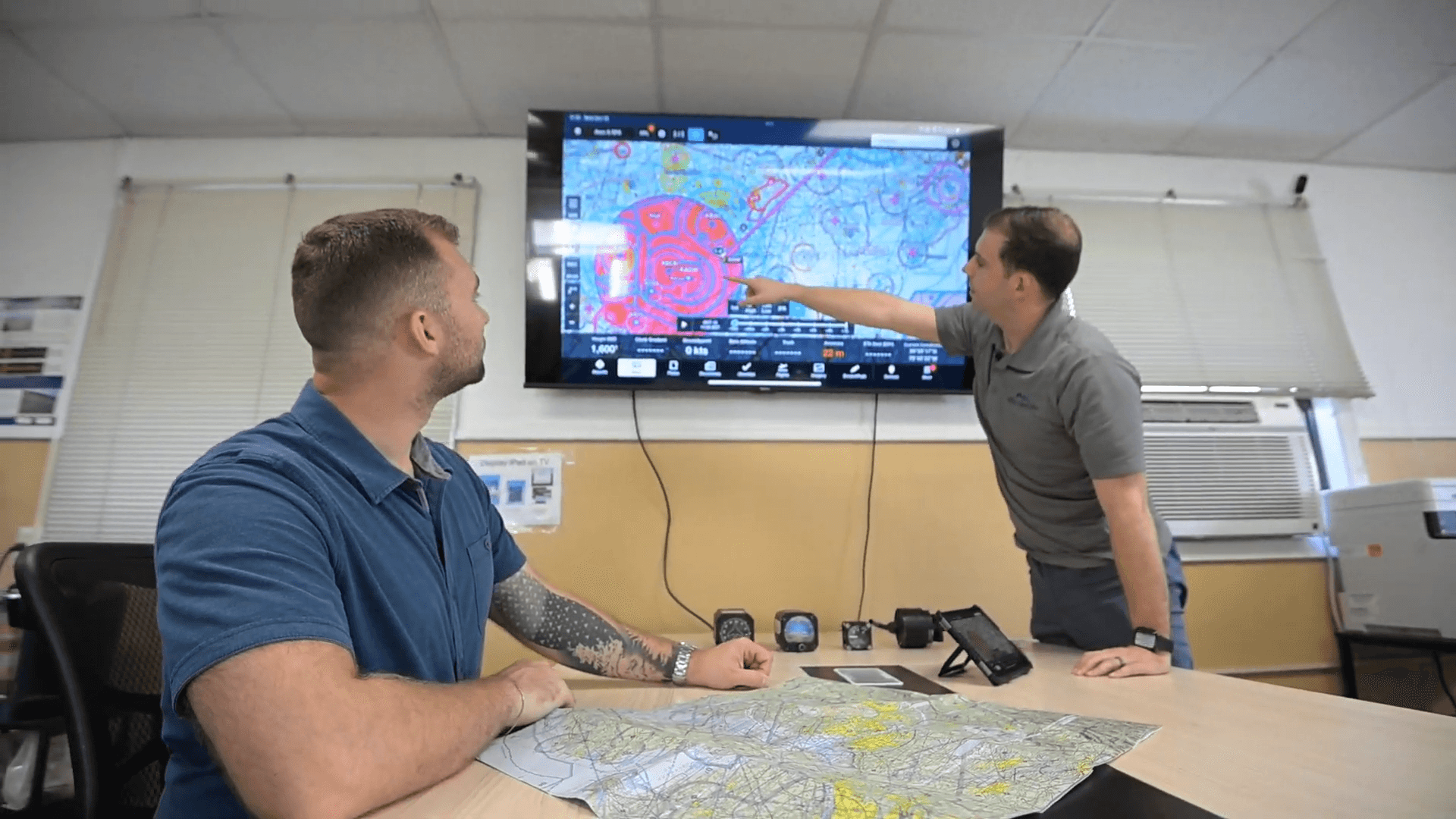 Flight instructor explaining aviation charts and flight training planning during ground school