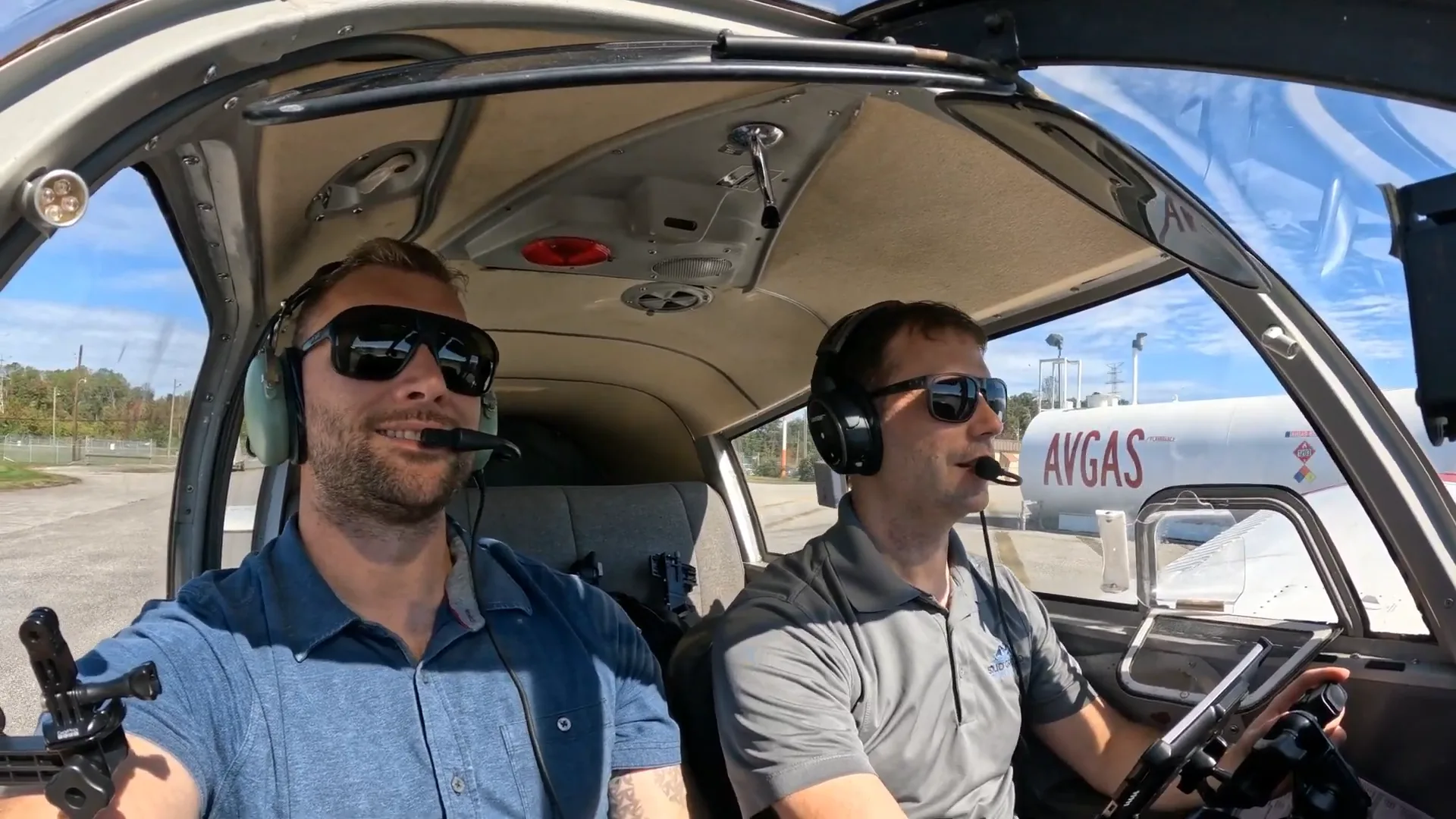 Two pilots smiling inside an airplane on the ground