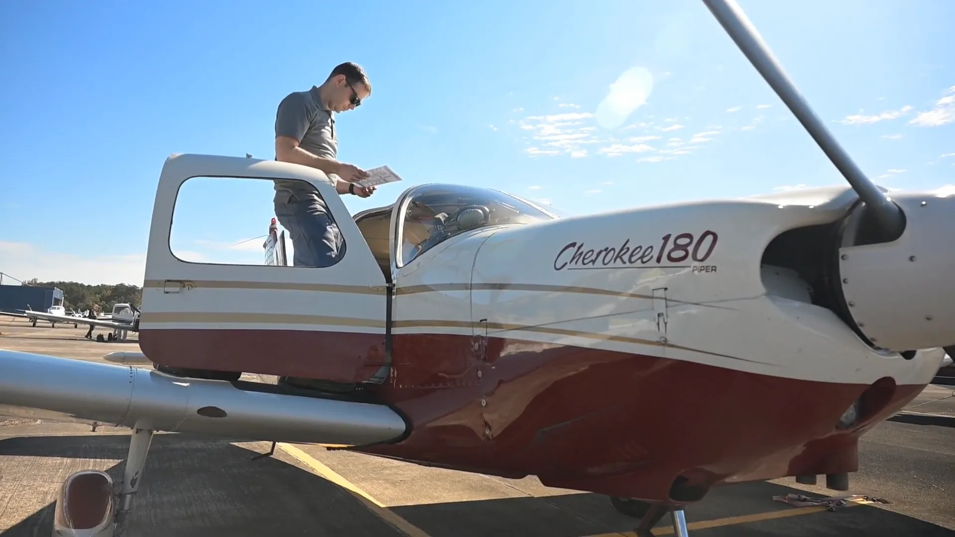 Pilot reviewing a chart on the wing of a training airplane before a cross-country flight
